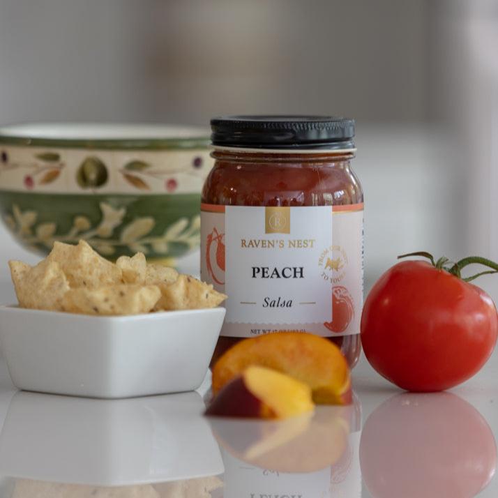 Peach Salsa Sitting Next to a Bowl of Chips with a Tomato and Peach Slices on the Counter