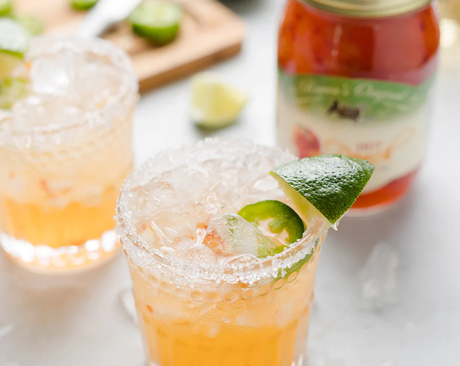 Hot Peach Margarita Cocktail Garnished with a Lime, Salt Rim, and Jalapeno Slices