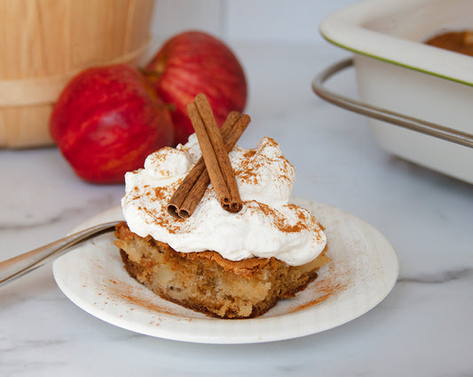 Slice of apple pie cake topped with whipped cream and cinnamon made with Raven's Nest Mulling Spice