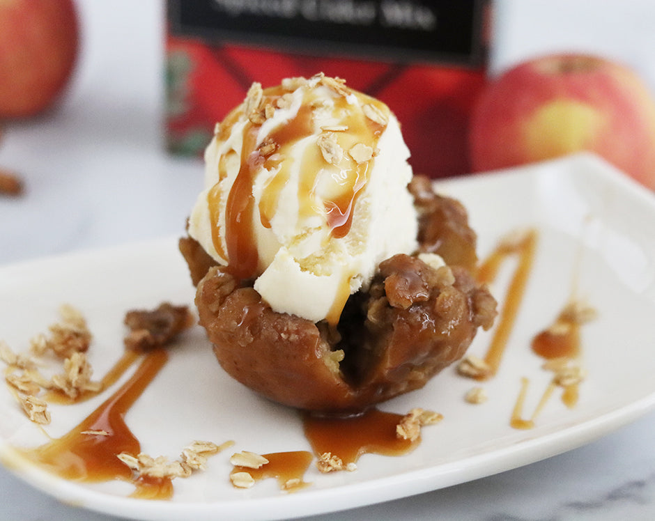 Sliced open baked apple topped with vanilla ice cream and caramel sauce