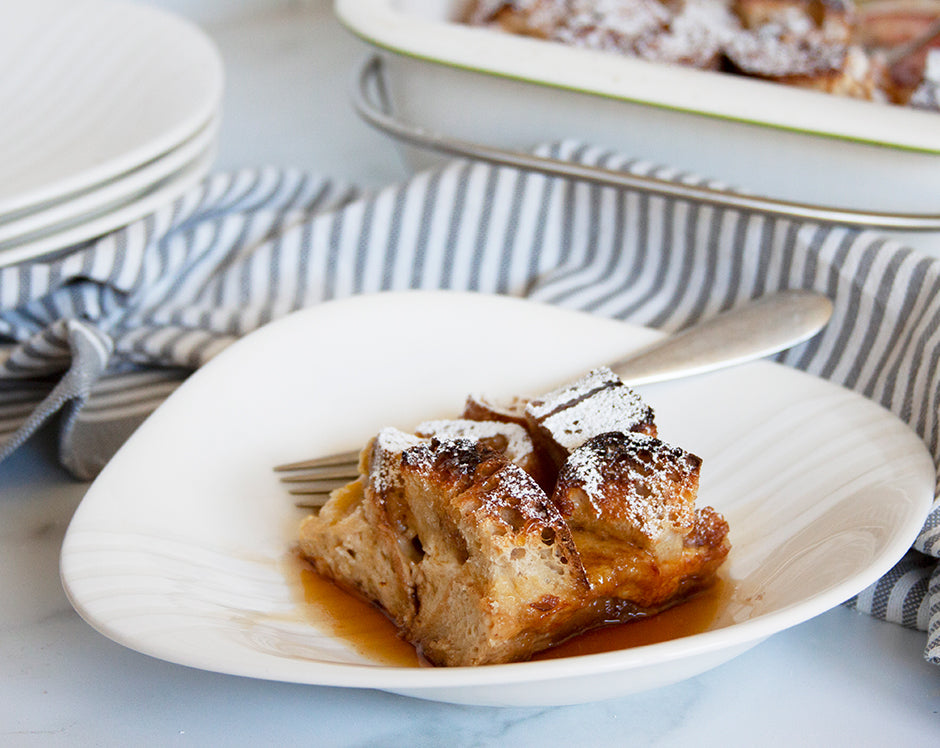 Slice of french toast casserole topped with powdered sugar and maple syrup