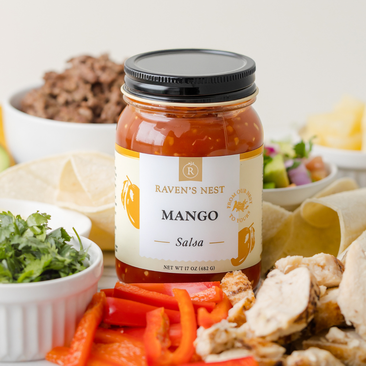 Peach Salsa Sitting Next to a Bowl of Chips with a Tomato and Peach Slices on the Counter