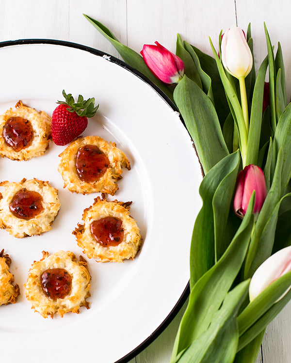 Strawberry jam coconut nest cookies on a plate with tulips