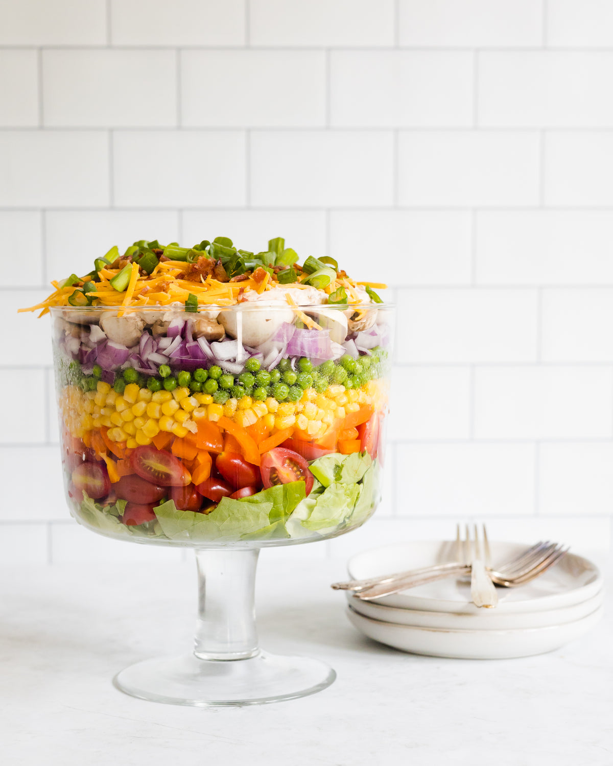 Layered salad with tomatoes, bell peppers, corn, peas, onions, mushrooms, cheese, and more topped with Raven's Garden Party dressing
