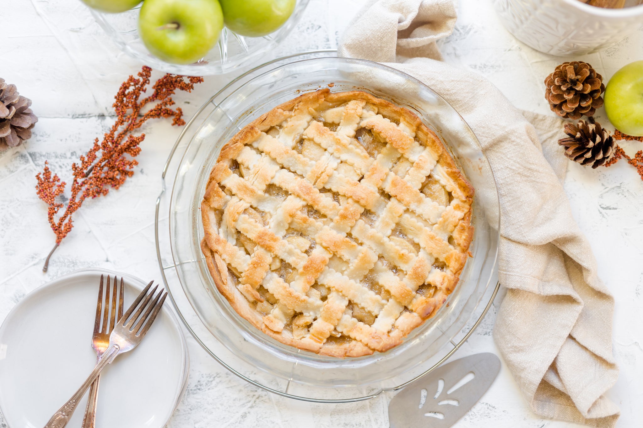 Lattice apple pie made with Raven's Nest mulling spice surrounded by fall foliage and apples