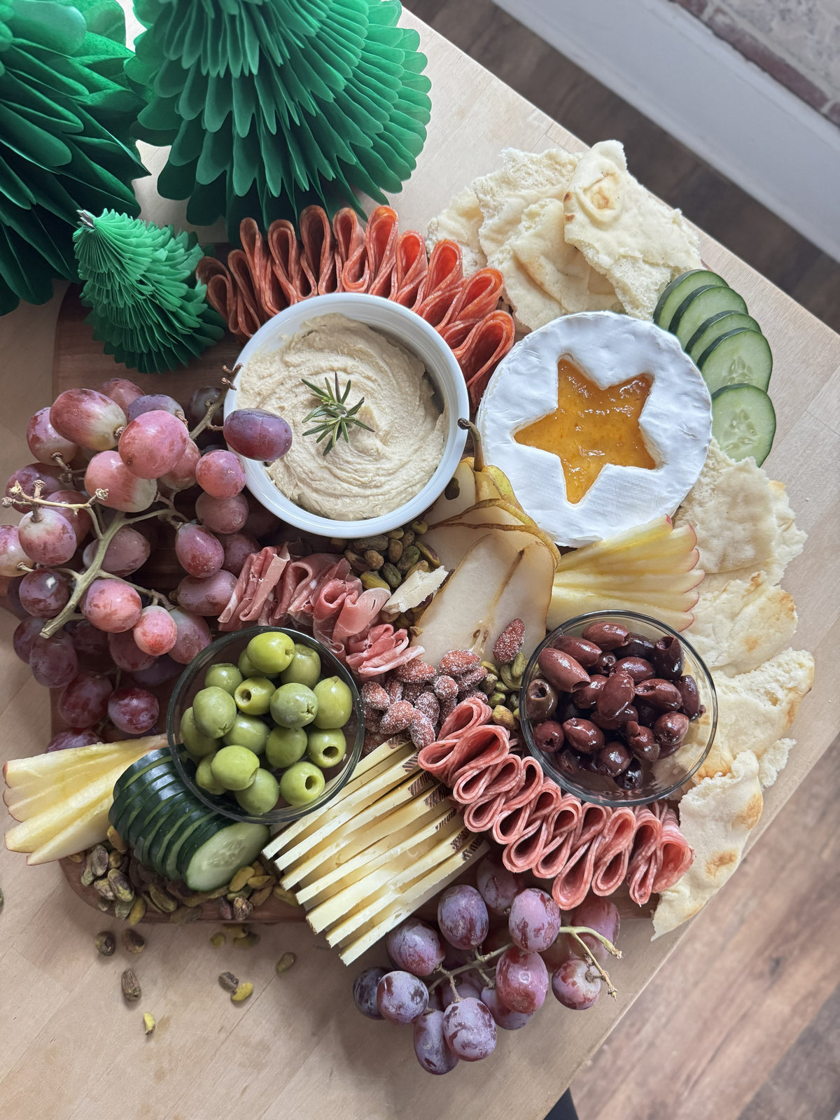 Create a simple Christmas Eve Shepherd’s Dinner board with Raven’s Nest Peach Habanero Jam, hummus, fresh fruit, meats, cheeses, olives, and naan.