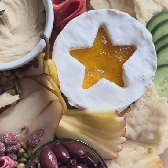 Create a simple Christmas Eve Shepherd’s Dinner board with Raven’s Nest Peach Habanero Jam, hummus, fresh fruit, meats, cheeses, olives, and naan.