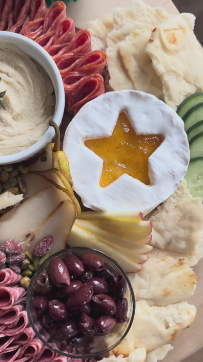 Create a simple Christmas Eve Shepherd’s Dinner board with Raven’s Nest Peach Habanero Jam, hummus, fresh fruit, meats, cheeses, olives, and naan.