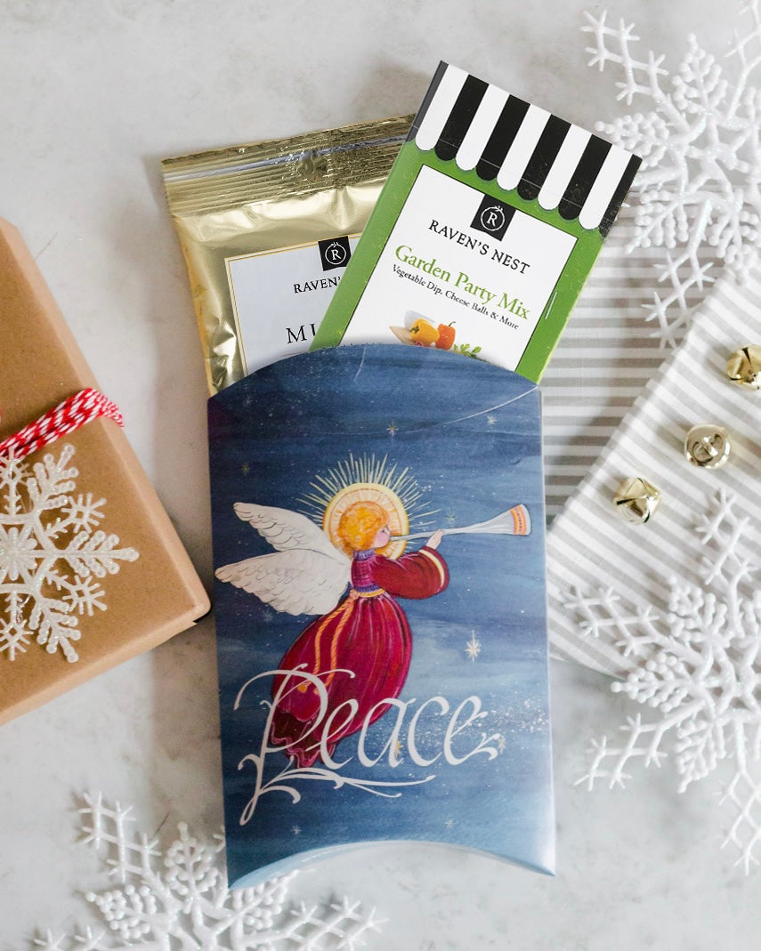 Packaged food items with a decorative angel card on a snowy background