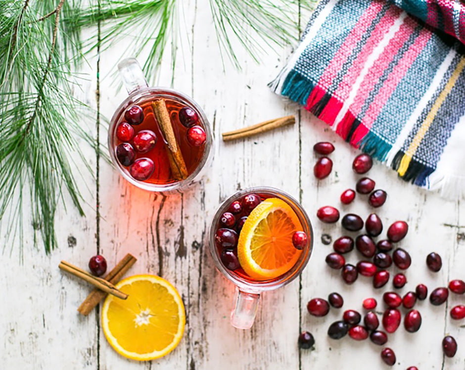 Mulled cider recipe made with Raven's Nest mulling spices, garnished with fresh oranges, cranberries, and cinnamon sticks in a winter scene