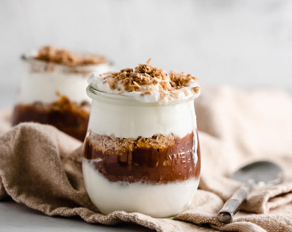 Pumpkin butter layered in glass mason jars with greek yogurt and topped with granola