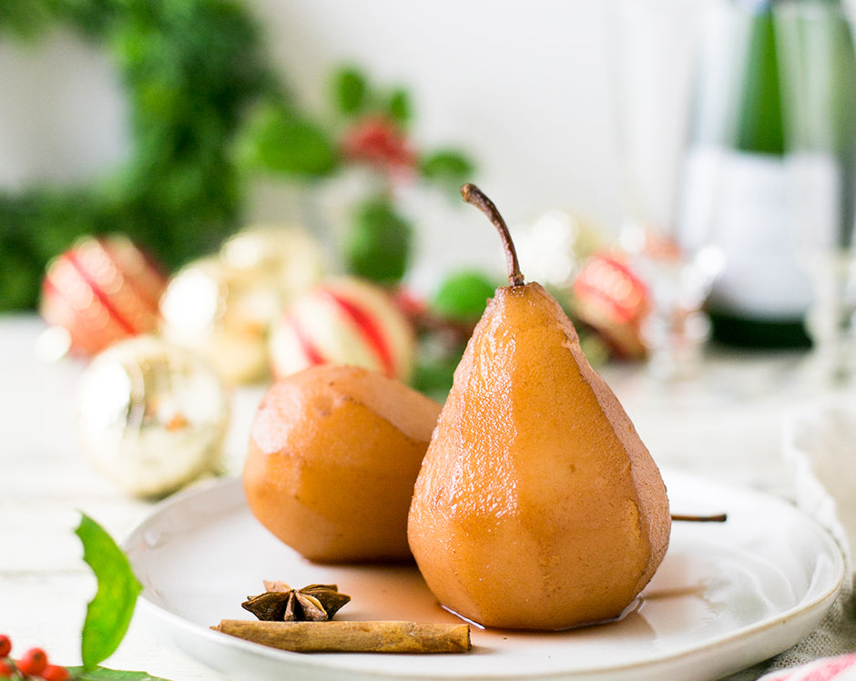 Drunken poached pears made with Raven's Nest Mulling spices garnished with anise and cinnamon in a Christmas table setting
