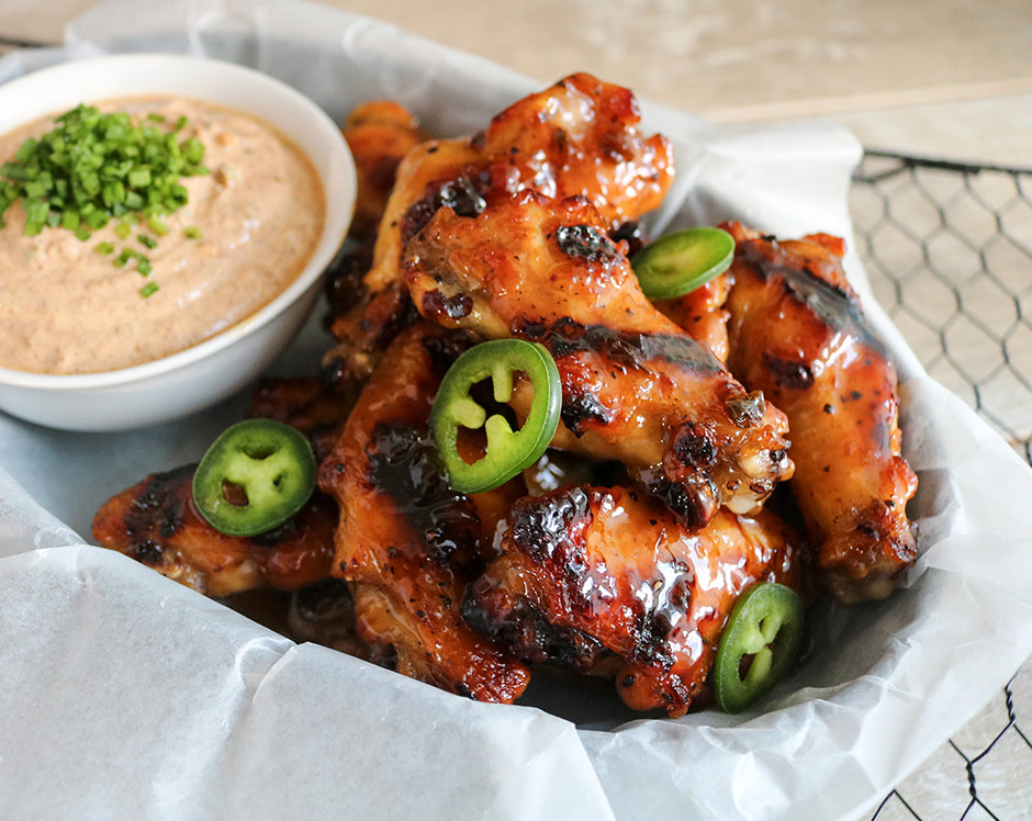 Sweet and spicy chicken wings made with a bbq sauce made from jam, Raven's Nest strawberry jalapeno jam served with a side of yogurt sauce made with Raven's Nest chili grande spice mix and garnished with fresh green onions and jalapenos
